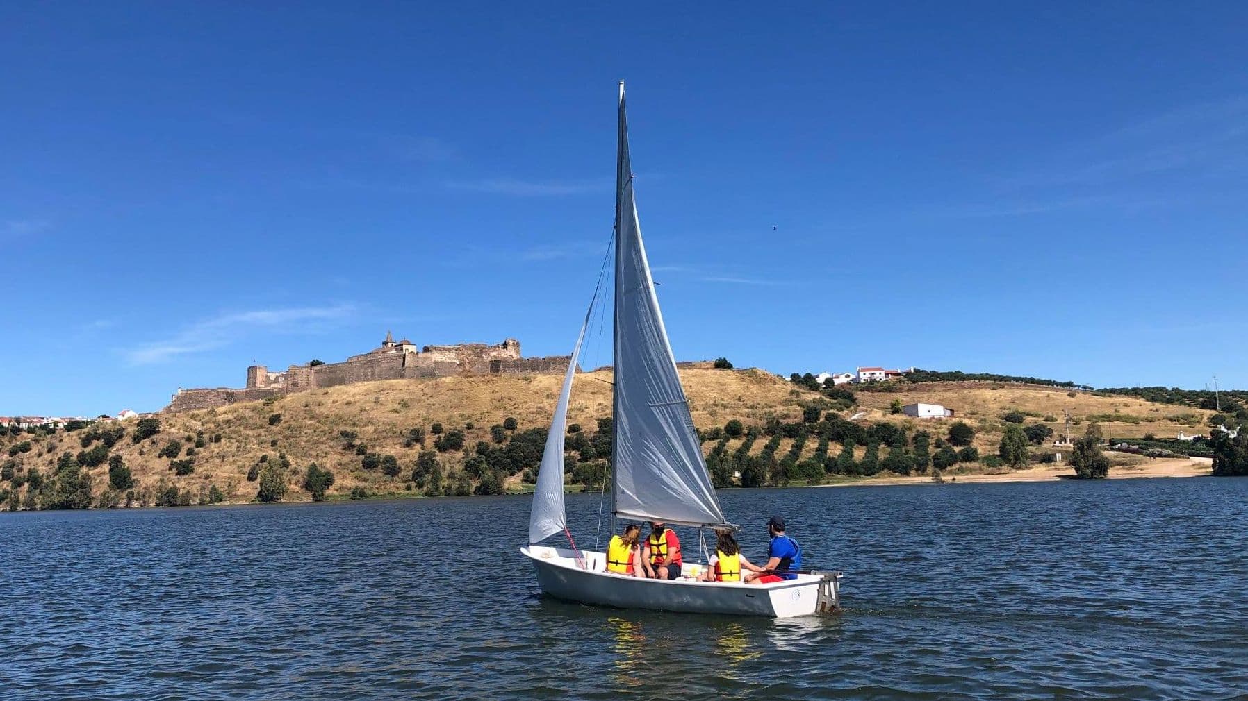 Regatistas navegando en el embalse de Orellana durante una prueba de vela ligera