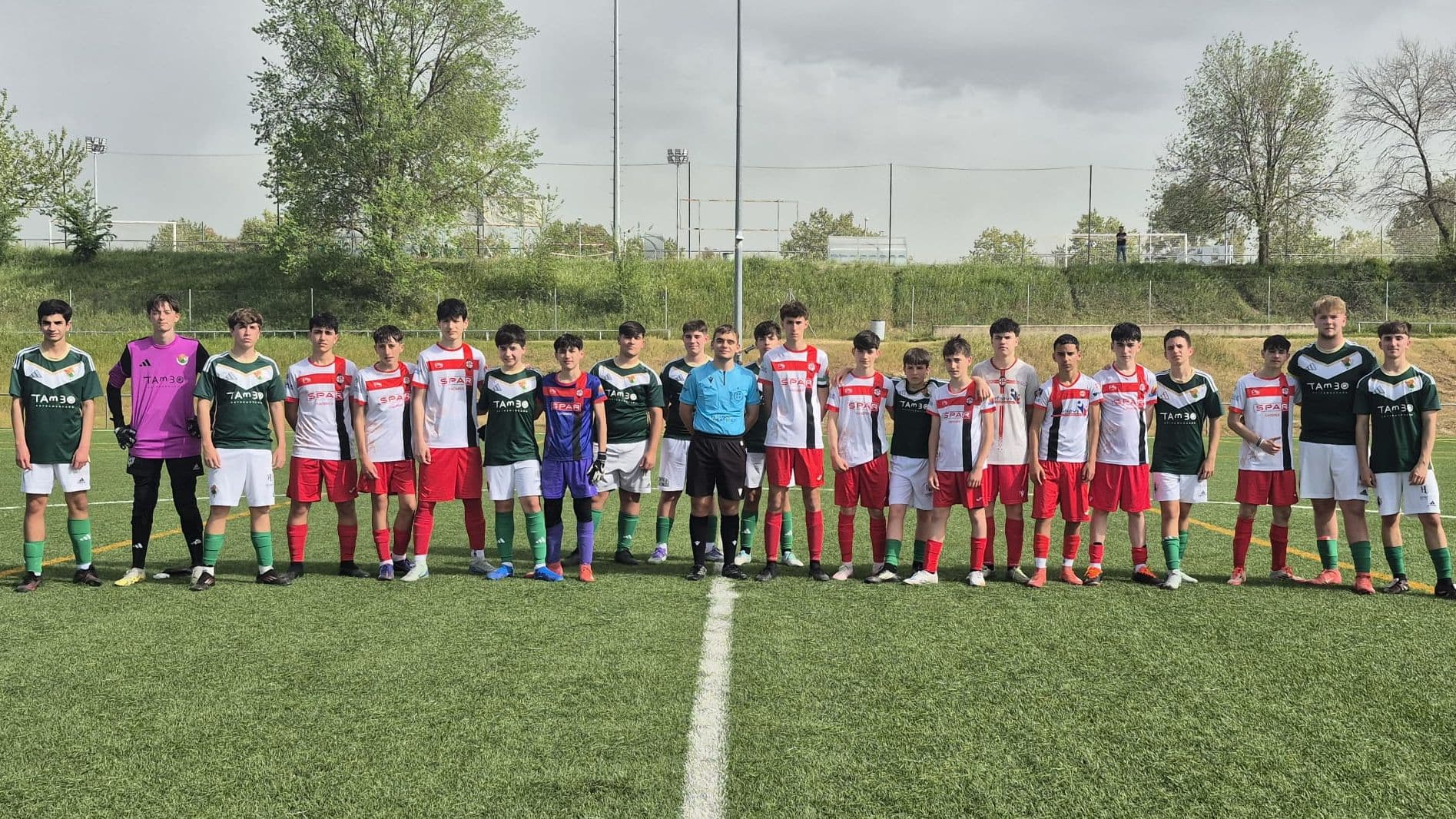 Jugadores de ambos equipos junto al árbitro en el protocolo lazos